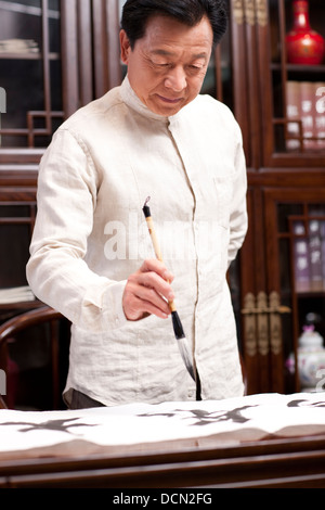 Senior man praticando la calligrafia in studio Foto Stock