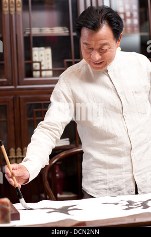 Senior man praticando la calligrafia in studio Foto Stock