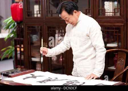 Senior man praticando la calligrafia in studio Foto Stock