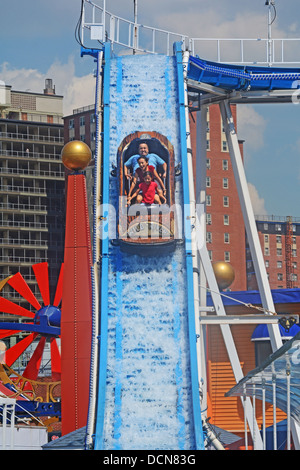 Con appartamento case in background una famiglia scorre il fiume selvaggio attrazione al luna park di Coney Island Brooklyn, New York Foto Stock