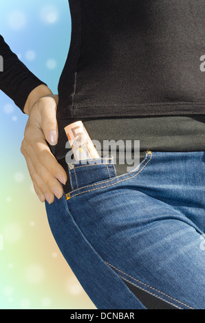 Rotolo di una cinquantina di banconote in euro in tasca laterale di jeans femminili sulla colorata sfondo sfocato Foto Stock