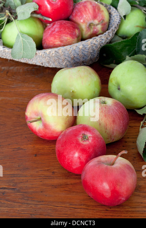 Molti mele fresche con foglie sul tavolo di legno vicino fino Foto Stock