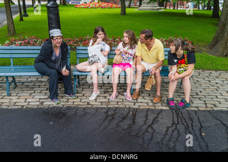 Una famiglia canadese di tre giovani ragazze e la loro madre e padre poggiare su una panchina nel parco in King Square, San Giovanni, Nova Scotia. Foto Stock