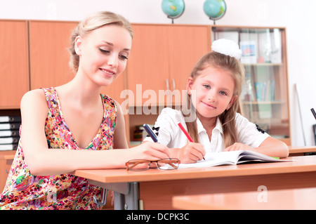 Insegnante seduta vicino allievo Foto Stock