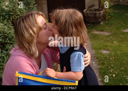 Madre baciando la sua figlia, primo giorno di scuola Foto Stock