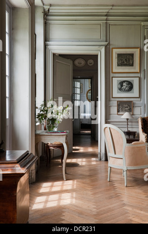 Vista attraverso le porte da un elegante salotto con pavimento in parquet di legno e pannelli di parete Foto Stock