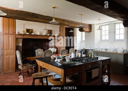 Isola di unità di piano di cottura in cucina con travi di legno a vista e grande camino aperto Foto Stock