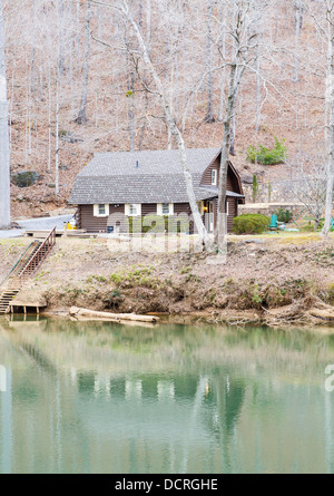 Un moderno log cabin sulla riva di un fiume calmo o lago in inverno Foto Stock