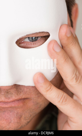 Malinconici e grave uomo di nascondersi dietro la maschera bianca Foto Stock