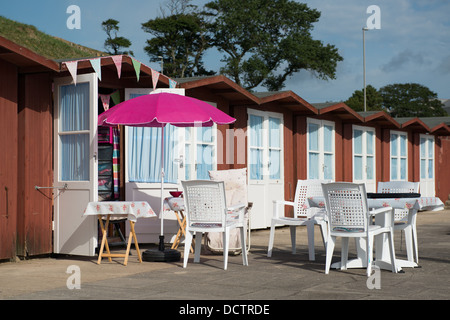 Beach Hut con tavoli e sedie e ombrellone fissati su una giornata d'estate a Swanage, Dorset Foto Stock