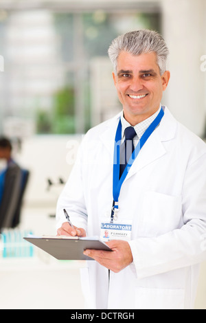 Sorridente senior scientist iscritto negli appunti di laboratorio Foto Stock