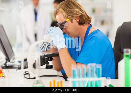 Maschio ricercatore medico lavora con microscopio in laboratorio Foto Stock