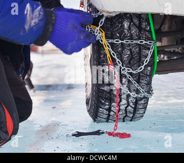 L'uomo installazione di catena da neve su auto Foto Stock