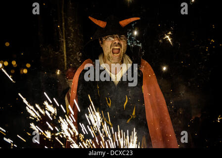 Barcellona, Spagna. 21 Agosto 2013: membro di 'la Vella de Grˆcia" rende i volti durante l'impostazione off il suo petardi durante il 'Correfocs' a 'Festa Major de Gracia'. Credito: matthi/Alamy Live News Foto Stock