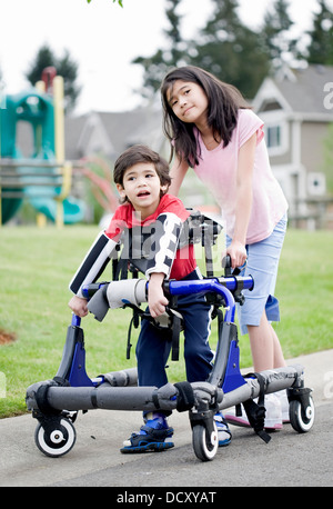 Big Sister aiutando i giovani disabili nel fratello walker Foto Stock