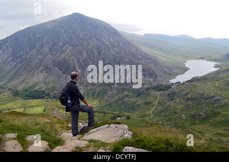 Uomo che guarda in basso vista verso Lyn Ogwen con il Welsh Mountain Pen yr Ole Wen dietro nel Parco Nazionale di Snowdonia Foto Stock