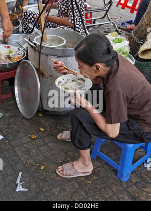 Senior donna vietnamita Pho mangiare per colazione. Cholon, Città di Ho Chi Minh (Saigon), Vietnam. Foto Stock