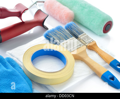 Strumenti di pittura su sfondo bianco. Rulli di vernice, spazzole, goccia panno, un nastro per mascheratura e guanti. Foto Stock