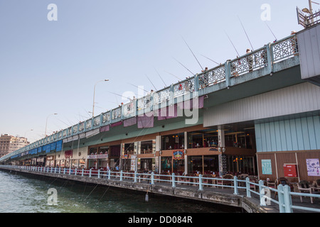 Gli uomini di pesca sul Ponte di Galata, e negozi e caffetterie sotto il ponte Galata, Istanbul, Turchia Foto Stock