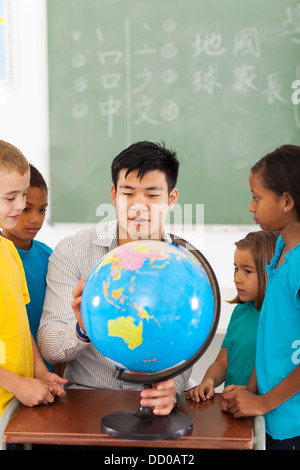 Gruppo gli studenti della scuola elementare e insegnante guardando il mondo in classe Foto Stock