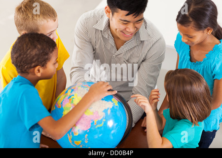 Allegro insegnante di scuola elementare con un globo insegnare la geografia Foto Stock