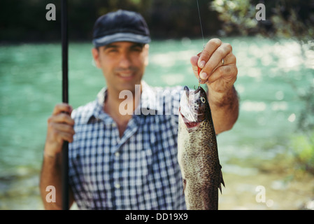 Metà adulto pescatore per vacanze sul fiume, rilassante e la pesca alla trota. Focus sui pesci Foto Stock