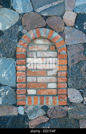 In mattoni arcuati finestra in un muro di pietra Foto Stock