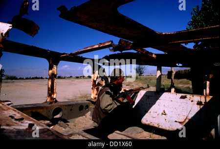 Fighter dell' Alleanza del Nord le protezioni la strada da Jabol Seraj o Jabal Saraj a Charikar durante la guerra con i Talebani. Egli prende la copertura in un distrutto costruite dai sovietici come trasporto di personale APC. Foto Stock