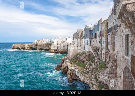 Edifici imbiancati costruito su una roccia sopra il bordo grotte marine che si affaccia sul mare di Polignano a Mare, Apuia, Italia meridionale Foto Stock