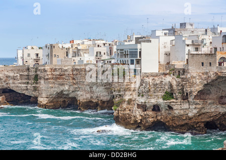 Edifici imbiancati costruito su una roccia sopra il bordo grotte marine che si affaccia sul mare di Polignano a Mare, Apuia, Italia meridionale Foto Stock