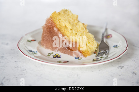 Fetta di Home limone al forno cospargere la torta con la glassa di zucchero superiore, su un fiore piastra modellata con una torta a forcella Foto Stock