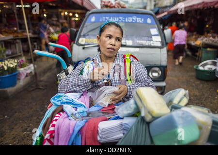 24 agosto 2013 - Bangkok, Thailandia - Una donna vendita di materiali per la pulizia attende i clienti su una strada di Khlong Toei Mercato in Bangkok. La Thailandia è entrato un Ã¢??technicalÃ¢?Â recessione questo mese dopo l'economia si è ridotto di 0,3% nel secondo trimestre di quest'anno. Il 0,3% la contrazione del prodotto interno lordo tra aprile e giugno a seguito di una caduta precedente del 1,7% durante il primo trimestre del 2013. La contrazione è imputabile a un calo della domanda di esportazioni, una caduta della domanda interna e una perdita di fiducia dei consumatori. Allo stesso tempo il valore del baht tailandese contro il dollaro USA ha dropp Foto Stock