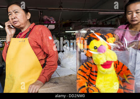 24 agosto 2013 - Bangkok, Thailandia - Una donna tigre Vendita di giocattoli di peluche utilizza il suo telefono cellulare in Bangkok. La Thailandia è entrato un Ã¢??technicalÃ¢?Â recessione questo mese dopo l'economia si è ridotto di 0,3% nel secondo trimestre di quest'anno. Il 0,3% la contrazione del prodotto interno lordo tra aprile e giugno a seguito di una caduta precedente del 1,7% durante il primo trimestre del 2013. La contrazione è imputabile a un calo della domanda di esportazioni, una caduta della domanda interna e una perdita di fiducia dei consumatori. Allo stesso tempo il valore del baht tailandese contro il dollaro USA è sceso in misura significativa da una alta o Foto Stock