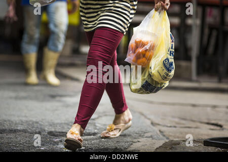 24 agosto 2013 - Bangkok, Thailandia - Una donna porta il suo shopping bags home lungo Sukhumvit Road di Bangkok. La Thailandia è entrato un Ã¢??technicalÃ¢?Â recessione questo mese dopo l'economia si è ridotto di 0,3% nel secondo trimestre di quest'anno. Il 0,3% la contrazione del prodotto interno lordo tra aprile e giugno a seguito di una caduta precedente del 1,7% durante il primo trimestre del 2013. La contrazione è imputabile a un calo della domanda di esportazioni, una caduta della domanda interna e una perdita di fiducia dei consumatori. Allo stesso tempo il valore del baht tailandese contro il dollaro USA è sceso in misura significativa da una h Foto Stock