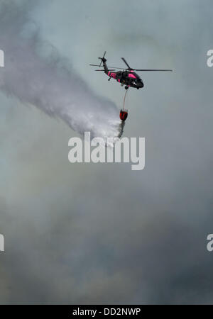 Prati Buck, CA, Stati Uniti d'America. 23 Ago, 2013. Una guardia nazionale Black Hawk scende un carico di acqua sul fuoco di RIM. Il cerchio Incendio di Stanislao National Forest lungo l'autostrada 120 continua a crescere. Secondo la US Forest Service come di venerdì 23 agosto 2013 pomeriggio il fuoco è cresciuto a 125,620 acri con solo il 5 per cento di contenimento più con le evacuazioni in Tuolumne City, CA e nelle aree vicine lungo la statale 108 corridoio. Il fuoco continua a diffondersi in diverse direzioni comprese verso il Parco Nazionale di Yosemite. Credito: Marty Bicek/ZUMAPRESS.com/Alamy Live News Foto Stock