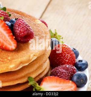 Piastra di colore bianco pieno di pancake con fragole lamponi e mirtilli Foto Stock