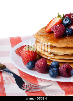Piastra di colore bianco pieno di pancake con Fragole Lamponi Mirtilli e miele su bianco Foto Stock