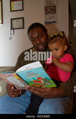 Maschio afro-americano ex detenuto la lettura alla sua giovane figlia. Questo detenuto è riuscito a ottenere un grado dopo il suo rilascio. Foto Stock