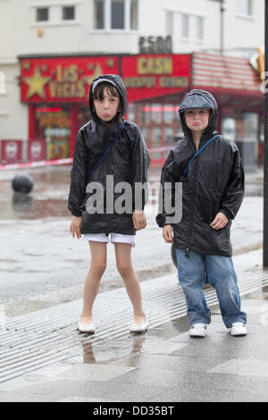 Southend, Essex, Regno Unito. 24 Ago, 2013. Fratello e Sorella da Wembley, Londra per una gita di un giorno al mare. STAND IN Heavy Rain e accanto alla strada allagata causato da un pozzo di liquame. 24/8/13 Credito: Graham whitby boot/Alamy Live News Foto Stock