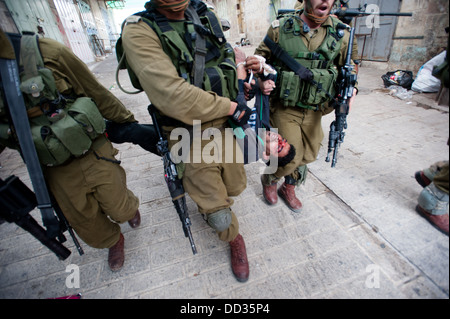 Soldati israeliani arrestare una gioventù palestinese, che mostra segni di essere battuti, a seguito di una dimostrazione a Hebron, West Bank. Foto Stock