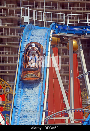 Con appartamento case in background una famiglia scorre il fiume selvaggio attrazione al luna park di Coney Island, Brooklyn New York Foto Stock