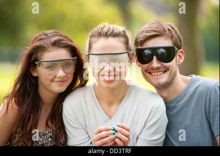 Tre giovani vestiti con minorazione visiva occhiali di simulazione Foto Stock