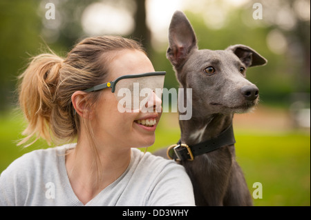 Giovane donna che indossa una disabilità visiva occhiali di simulazione con il cane Foto Stock