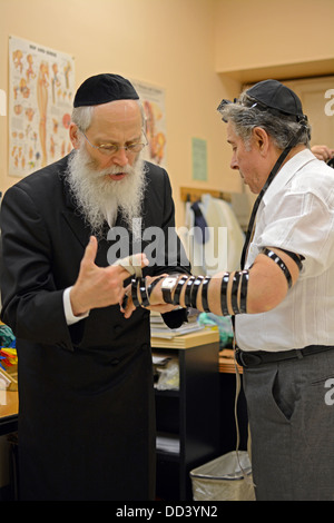 Un religioso rabbino ebreo in visita a un senior center nella spiaggia di Brighton Brooklyn incoraggiare gli immigrati russi per mettere su phylacteries Foto Stock