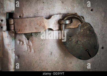 Vecchia serratura arrugginita appeso sulla porta di metallo. Primo piano Foto Stock