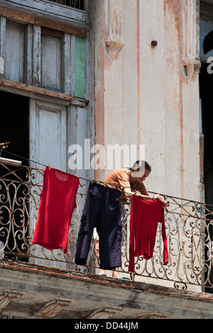 Una donna si blocca il suo servizio lavanderia su un balcone decrepito in Havana Cuba. Foto Stock
