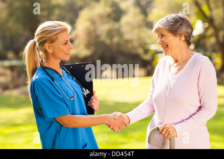 Bella la metà di età handshaking infermiere senior all'esterno del paziente Foto Stock