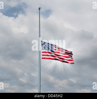 La metà del montante di bandiera americana concetto con il simbolo degli Stati Uniti volare a bassa quota sul pennone o personale in un giorno nuvoloso con un bagliore di sun come icona di onore di rispetto e di lutto per i caduti heros. Foto Stock