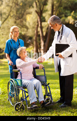 Amichevole maschio medico saluto senior all'esterno del paziente Foto Stock