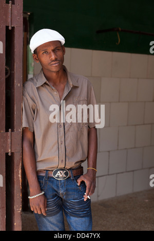 Un ritratto di un maschio di fumare una sigaretta, in piedi in un portale con un cappuccio bianco a l'Avana, Capitol città di Cuba Foto Stock